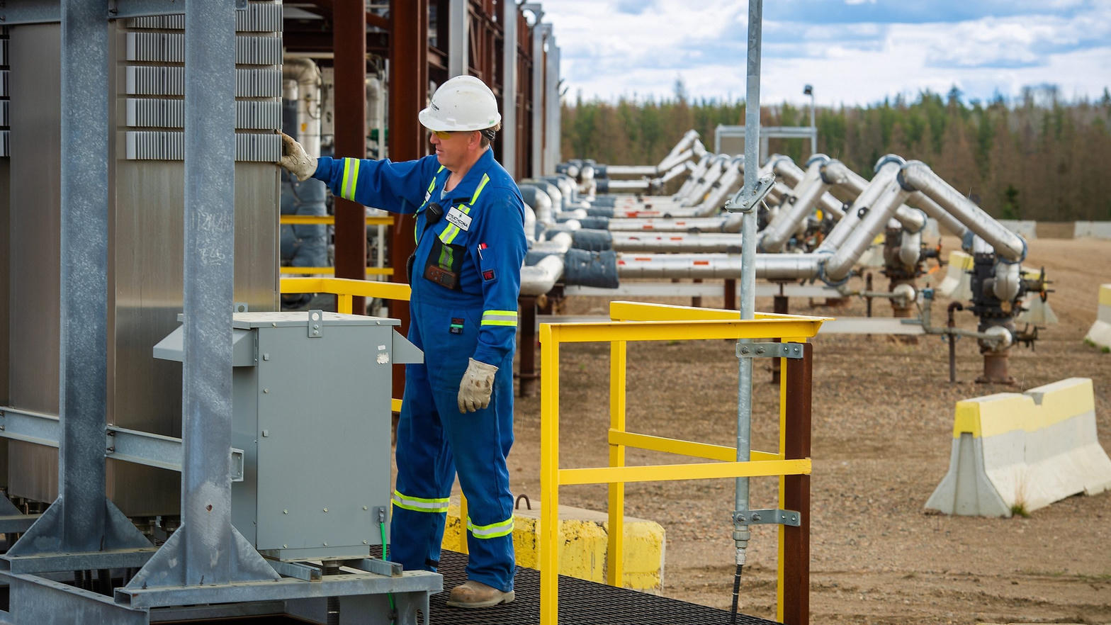 Oilfield worker in coveralls and hard hat on site
