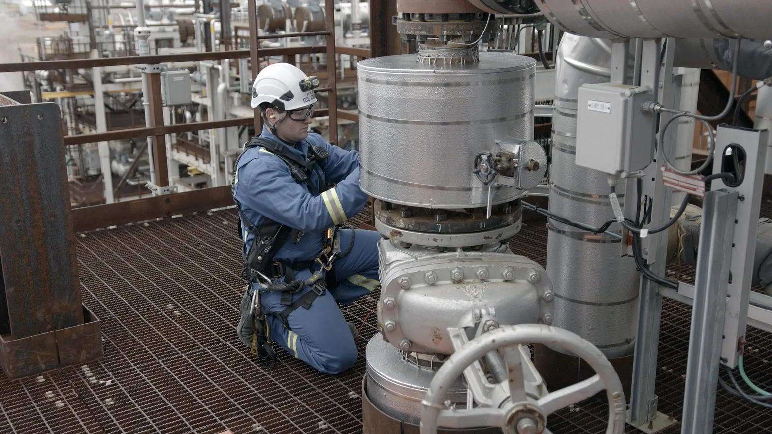 Technician in PPE performing inspection on industrial equipment